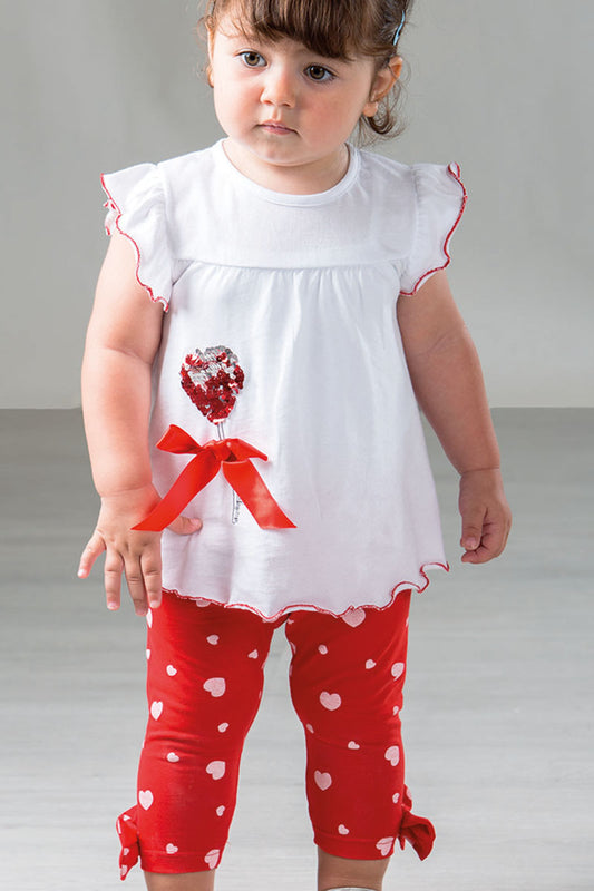 Completo: t-shirt in cotone con taglio carrè, paillettes reversibili e fiocco applicato + pinocchietto in cotone elasticizzato fantasia cuori con fiocchi sul fondo